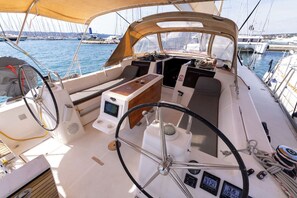 Das Deck eines Bootes mit Steuer, Bedienfeld und Sitzgelegenheiten.