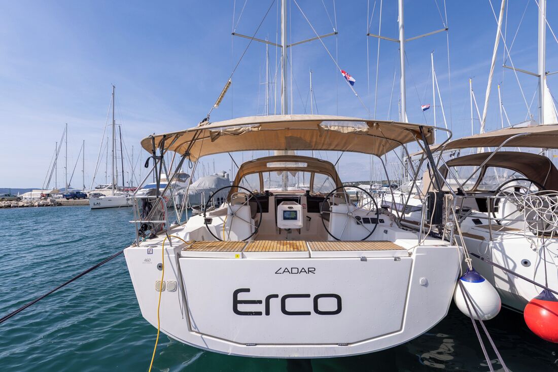 A sailboat named 'Erco' docked at a marina with multiple other boats in the background.