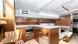 Een compacte keuken met houten kastjes, een inbouwoven en een klein eethoekje met een bank.