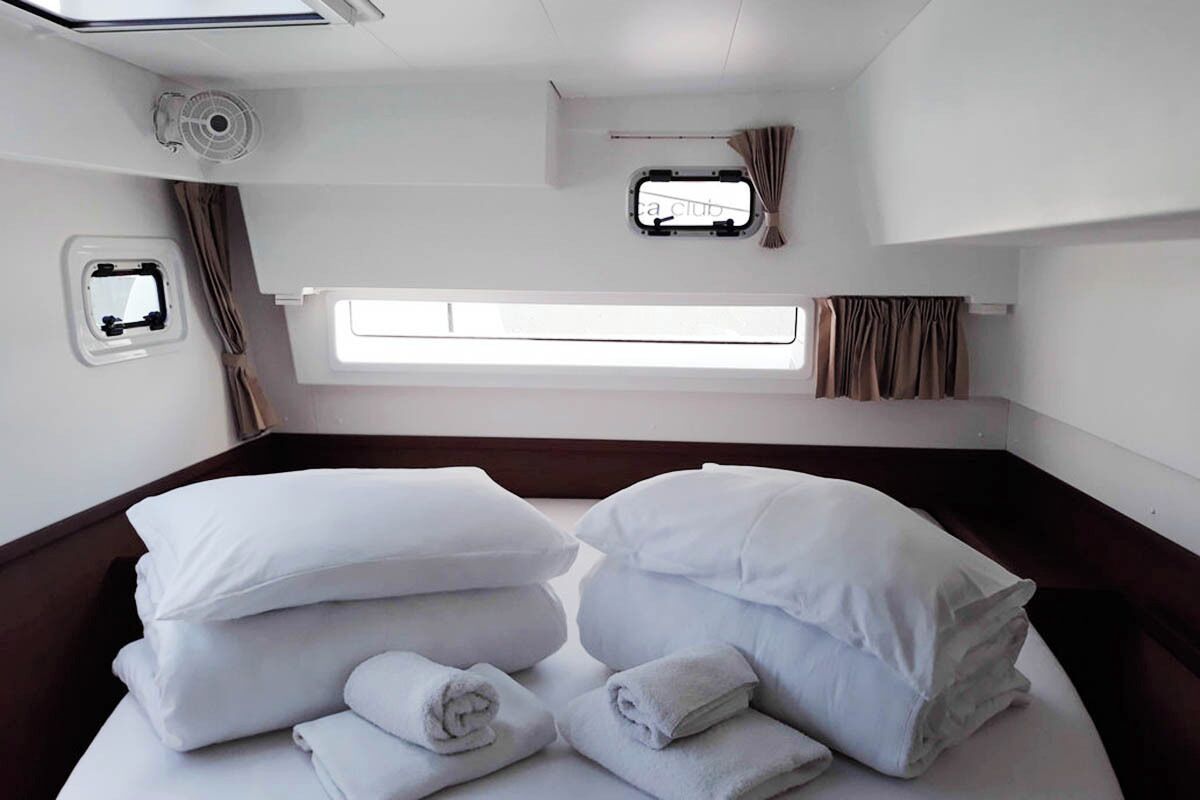 Une chambre d’hôtel avec un lit, des oreillers, une fenêtre, un ventilateur et des rideaux.