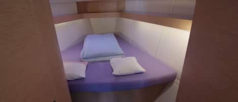 A small, enclosed cabin with a bed, a ceiling light, and a door.