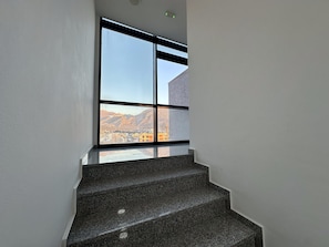 A staircase with a view of mountains through a large window. - Alula Apartments "1" (Bar)