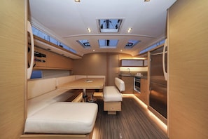 A compact, well-lit interior with a dining area, seating, a kitchenette, and skylights. - Sun-Kissed Sailing Adventure in Zadar, Croatia (Biograd na moru)