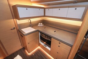A compact kitchen with wooden cabinets, a built-in oven, and a sink. - Sun-Kissed Sailing Adventure in Zadar, Croatia (Biograd na moru)
