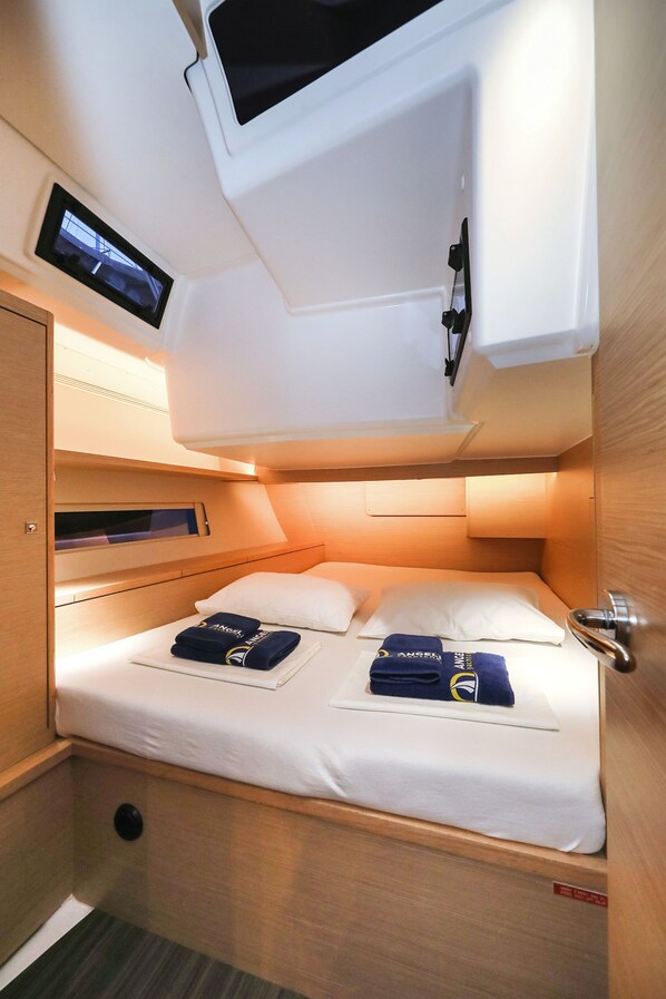 A compact, well-lit cabin with a bed, pillows, and a small TV mounted on the ceiling. - Sun-Kissed Sailing Adventure in Zadar, Croatia (Biograd na moru)