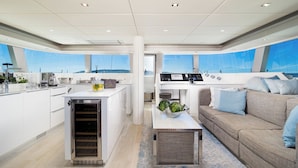 Une cuisine moderne avec un îlot central, un coin repas doté d’un canapé et une vue sur la mer.