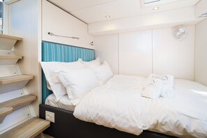 A neatly made bed with white linens, a blue-striped headboard, and a small bedside table with a lamp. - Sun-Kissed Sailing Adventure in Split, Croatia (Kaštel Gomilica)