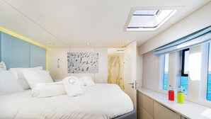 Une chambre moderne avec un lit, une fenêtre donnant sur un beau paysage, un puits de lumière et un mur orné d’un motif.
