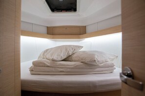 A compact, well-lit room with a bed, a small window, and a door. - Sun-Kissed Sailing Adventure in Istria, Croatia (Pula)