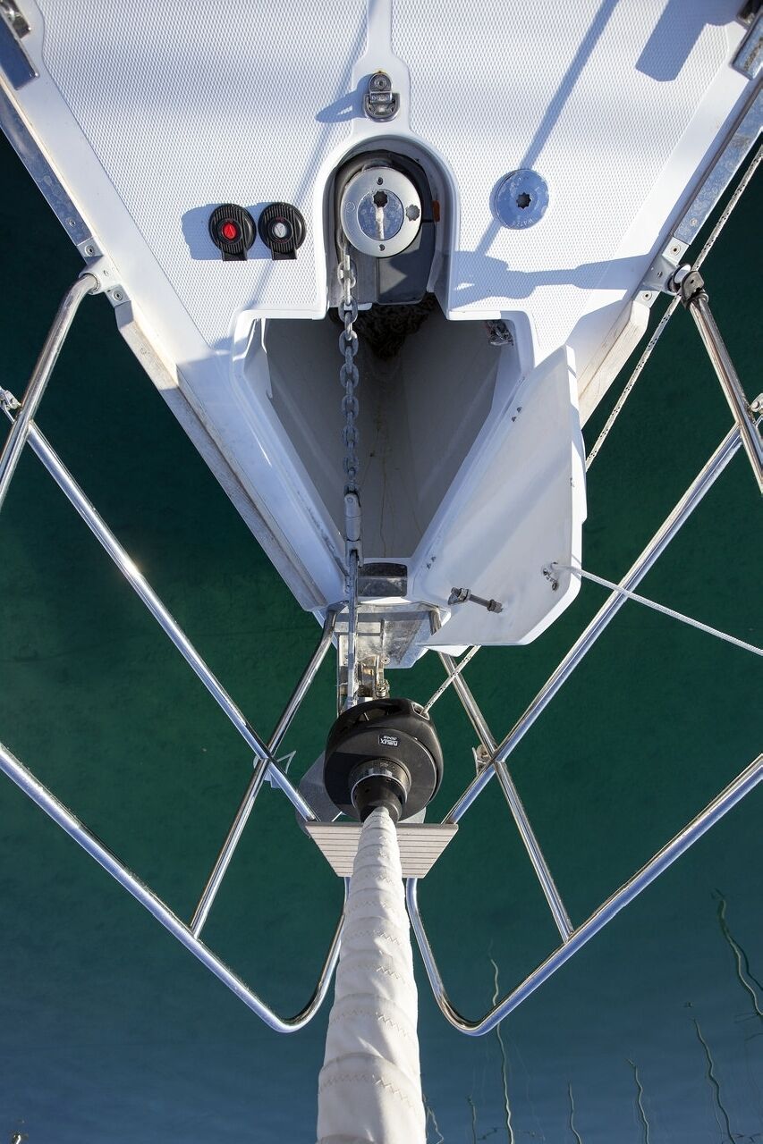 A boat's bow with a white deck, metal railings, and a chain.