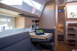A compact interior with a bed, a small table with a laptop, and a window. - Sun-Kissed Sailing Adventure in Istria, Croatia (Pula)