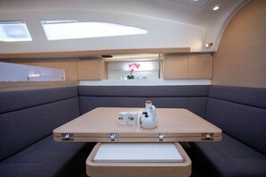 A compact kitchen area with a countertop, cabinets, and a small table with a vase and two boxes. - Sun-Kissed Sailing Adventure in Istria, Croatia (Pula)