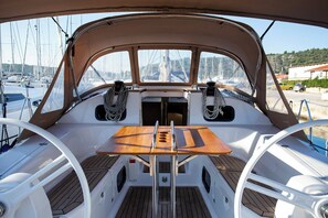 A boat's deck with a central table, two seating areas, and a view of other boats and land. - Sun-Kissed Sailing Adventure in Istria, Croatia (Pula)