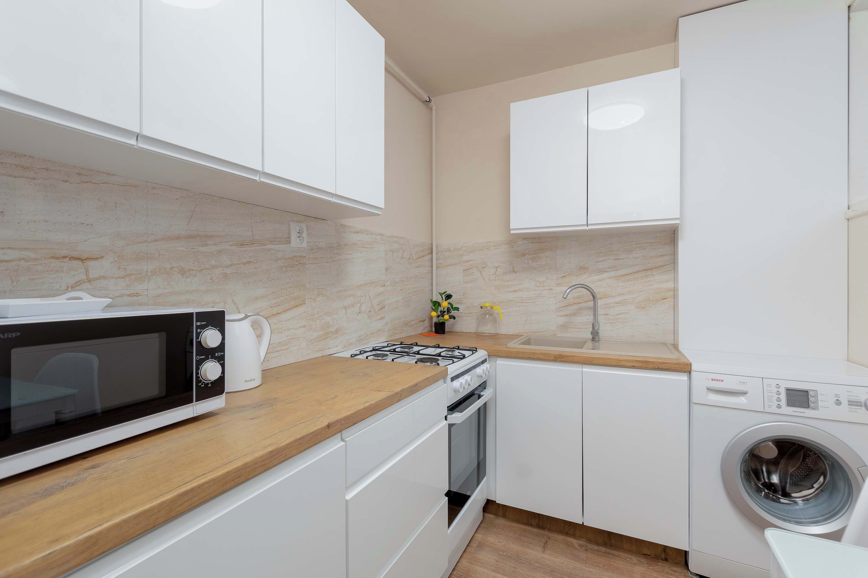 Una cocina compacta equipada con microondas, estufa, horno, lavaplatos y lavadora.
