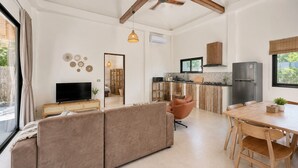 A modern living room with a sofa, TV, and dining area with a table and chairs. - 3-Bedroom Private House in Koh Phangan – Sleeps 6 (Surat Thani)