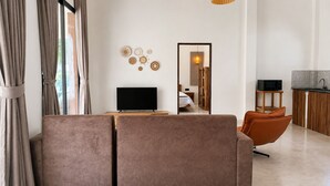 A modern living room with a flat-screen TV, a sofa, and a dining area with a kitchen in the background. - 3-Bedroom Private House in Koh Phangan – Sleeps 6 (Surat Thani)