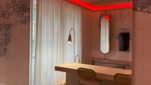 Ein modernes Badezimmer mit einem großen Spiegel, einem Waschbecken und zwei Hockstühlen.