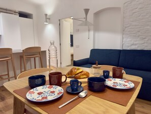 A dining table with plates, cups, a croissant, and a bottle. - LuxurySuite44: Historic Residence on a Staircase with a Jacuzzi, Located Between Downtown and the Train Station (La Spezia)