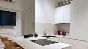 Eine moderne Küche mit weißer Arbeitsplatte, einem schwarzen Spülbecken und Holzstühlen.