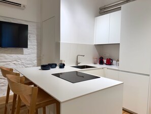 A modern kitchen with a white countertop, a black sink, and wooden chairs. - LuxurySuite44: Historic Residence on a Staircase with a Jacuzzi, Located Between Downtown and the Train Station (La Spezia)