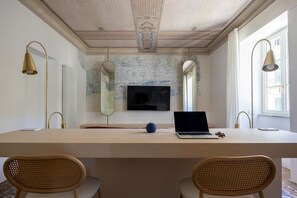 A room with a long table, two chairs, a laptop, a TV, and decorative mirrors. - LuxurySuite44: Historic Residence on a Staircase with a Jacuzzi, Located Between Downtown and the Train Station (La Spezia)