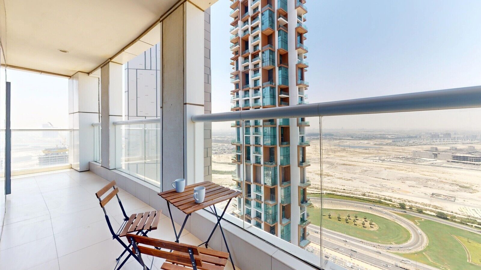 A balcony with a view of a tall building and a highway.