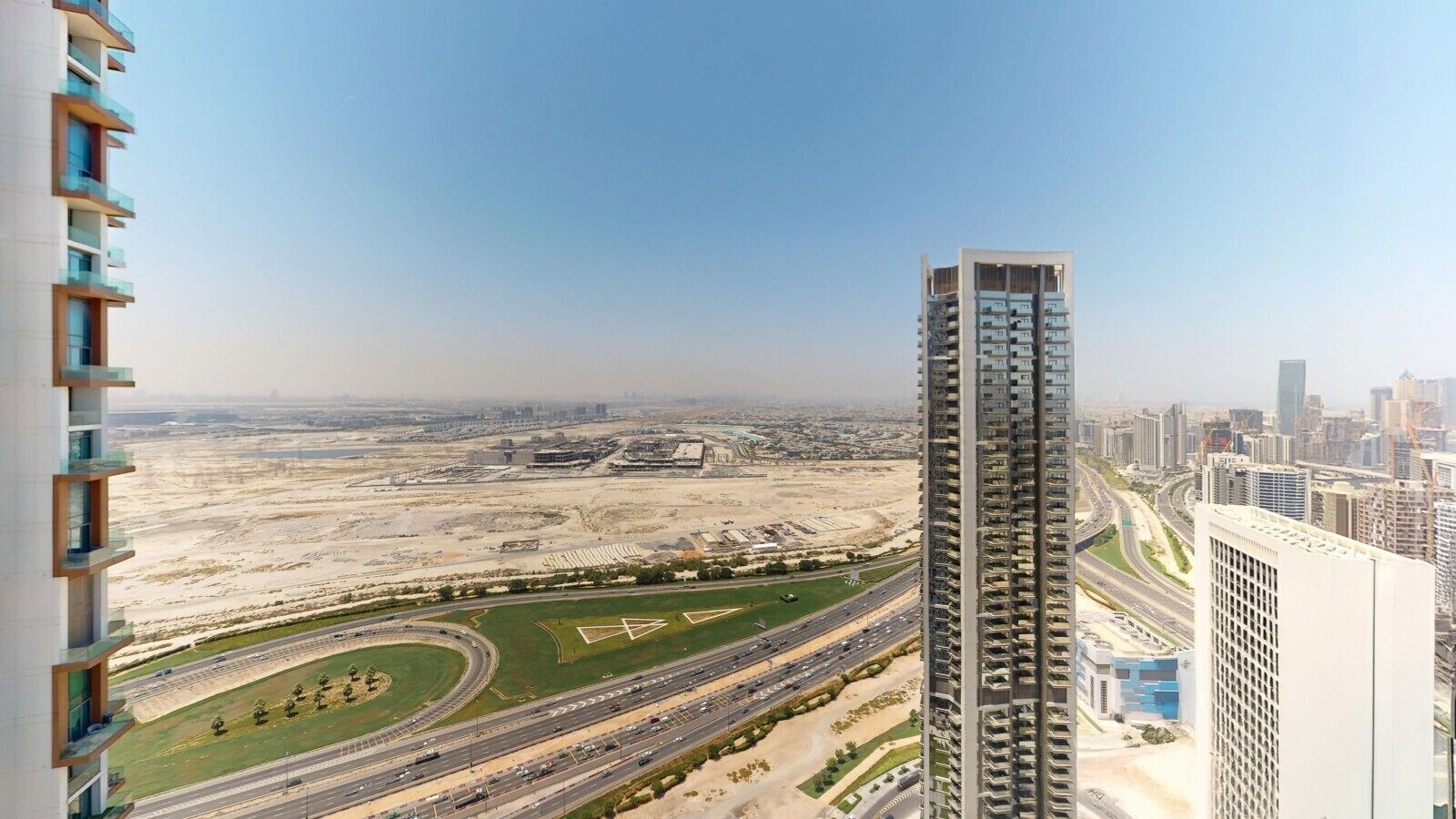 A high-rise building with a view of a highway and surrounding urban area.