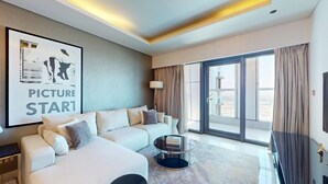 Ett modernt hotellrum med en soffa, ett soffbord, en TV och ett stort fönster med gardiner.