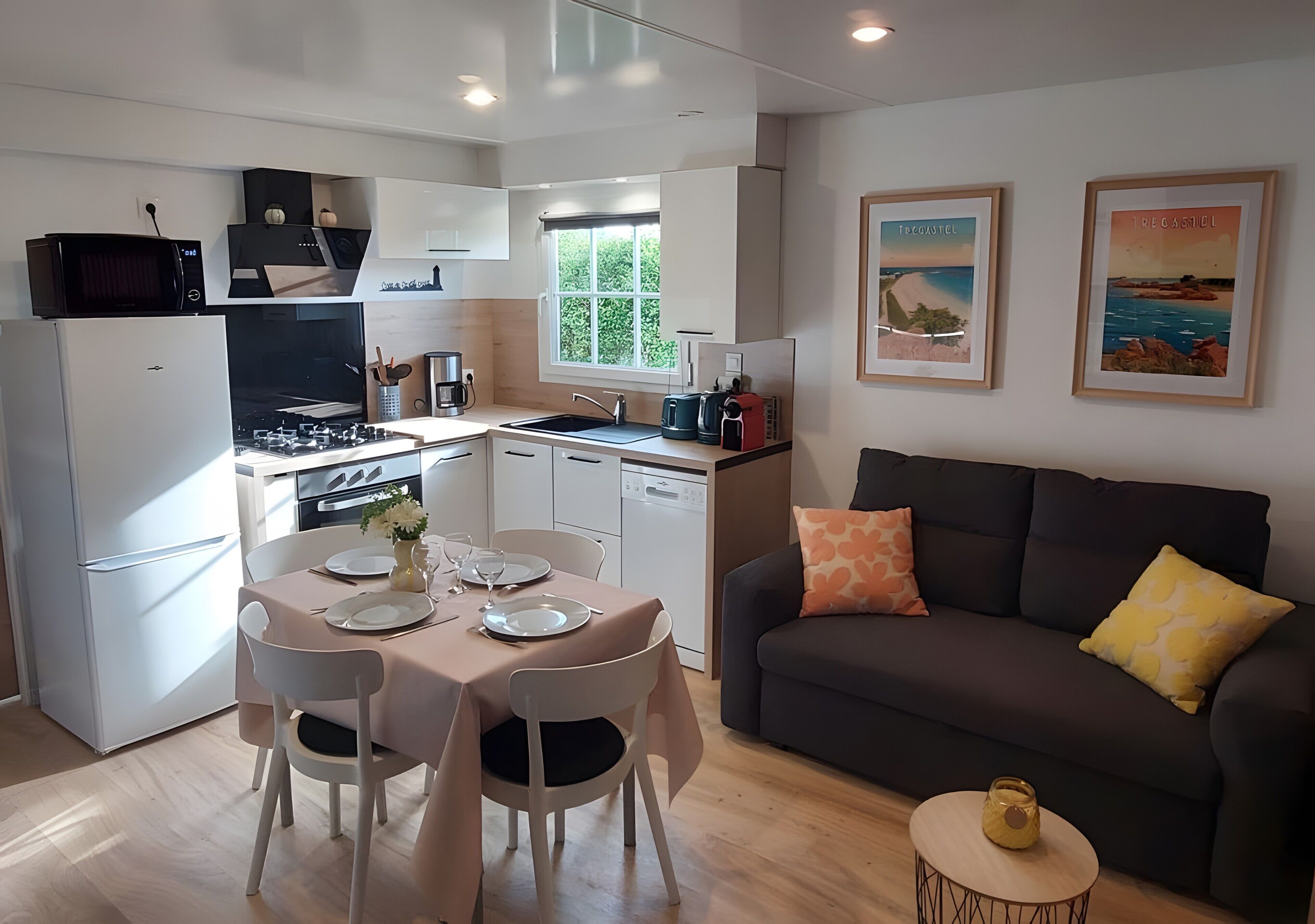 Een compacte keuken met een eethoek, een bank en twee ingelijste foto’s aan de muur.