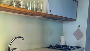 A kitchen with a stainless steel sink, a gas stove, wooden cabinets, and a countertop.