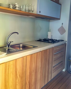 Eine Küche mit Spülbecken aus Edelstahl, einem Gasherd, Holzschränken und einer Arbeitsplatte.