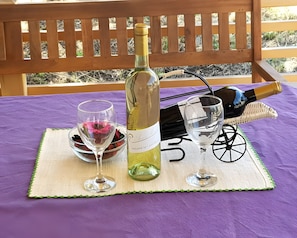A bottle of wine, two wine glasses, and a basket on a table with a purple tablecloth.