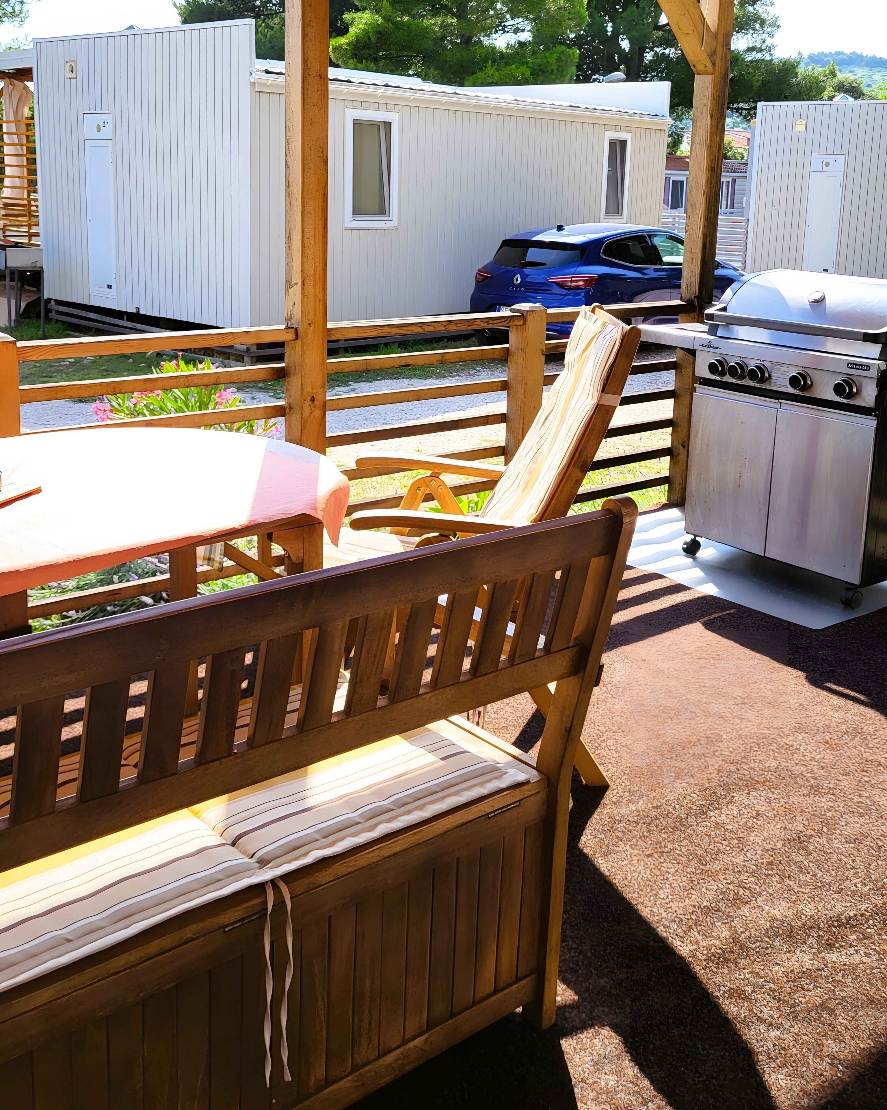 Banco y mesa de madera con una parrilla y cocina portátil en un patio trasero.