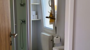 Une salle de bain comprenant des toilettes, un bidet, une douche et une fenêtre donnant sur l’extérieur.
