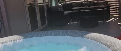 Ein Whirlpool, umgeben von Gartenmöbeln, einer überdachten Terrasse und einer Schiebetür.