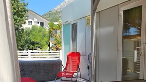 A covered outdoor area with a table, a red chair, and a wicker chair.