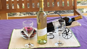 A bottle of wine, two wine glasses, and a basket on a table with a purple tablecloth.