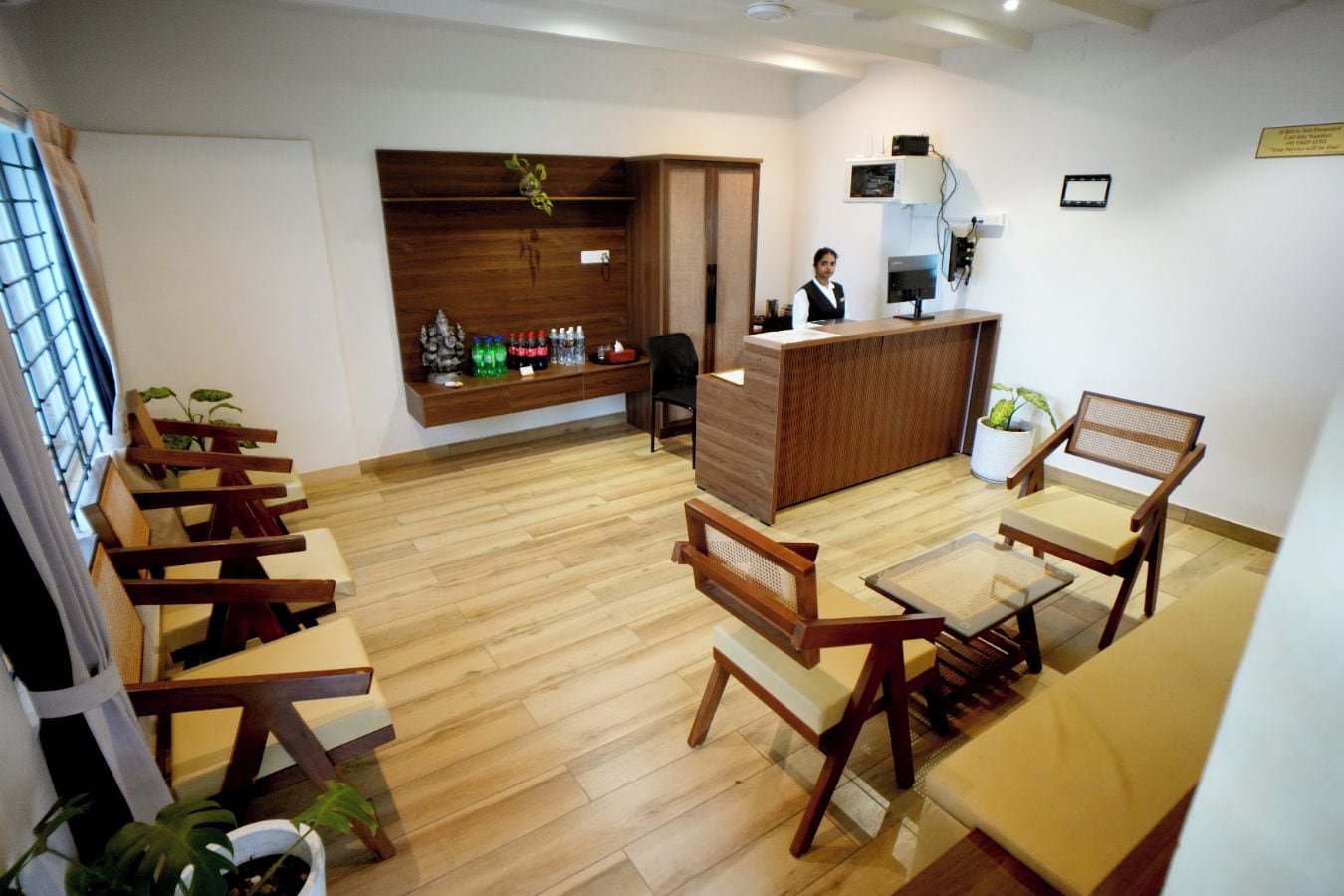 A reception area with a wooden reception desk, a receptionist, and a seating area with wooden chairs and tables.