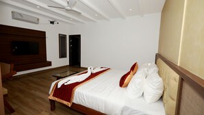 A bedroom with a bed, a television, a ceiling fan, and a wooden floor.
