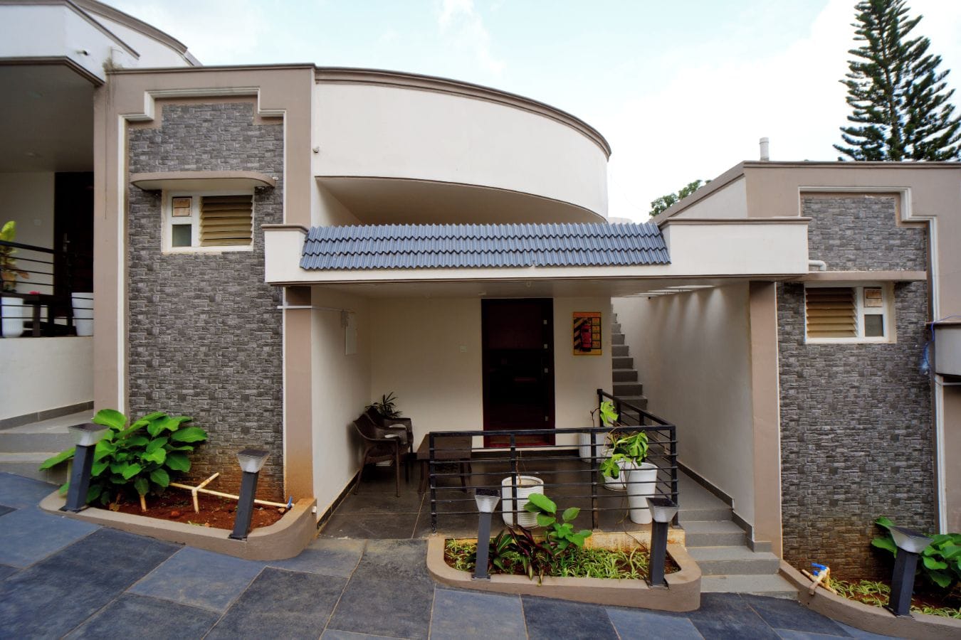 Una casa moderna con un diseño curvo, un porche cubierto y una escalera que lleva a la entrada.