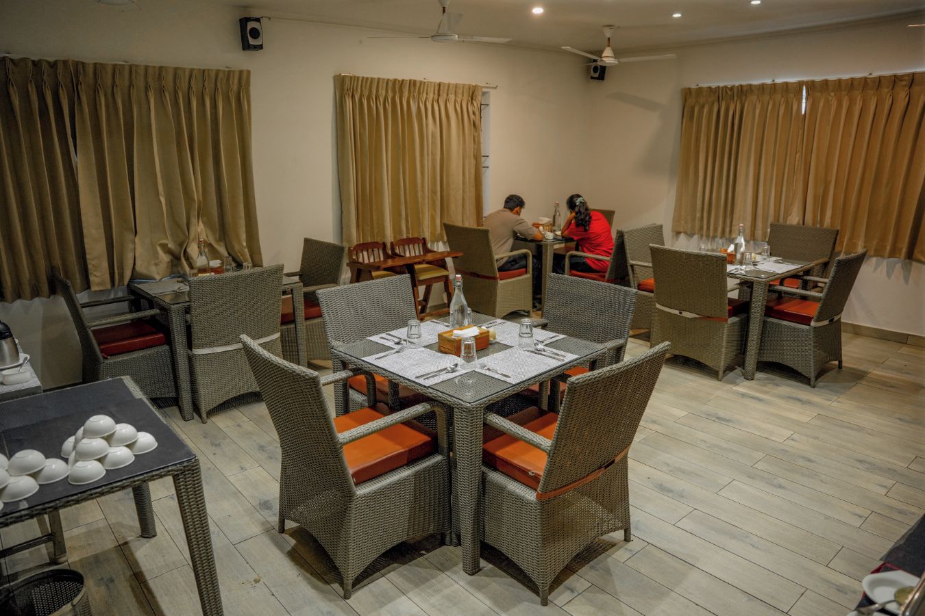A dining area with wicker furniture and a table set for two.