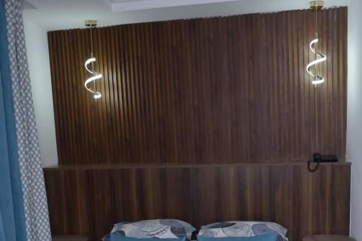 Un lit avec une tête de lit en bois, deux tables de chevet et une couverture bleue.