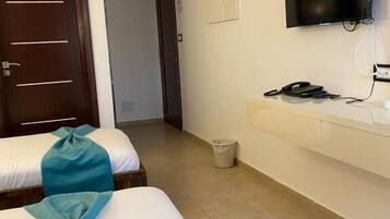A hotel room with two beds, a TV, a desk, and a trash bin.