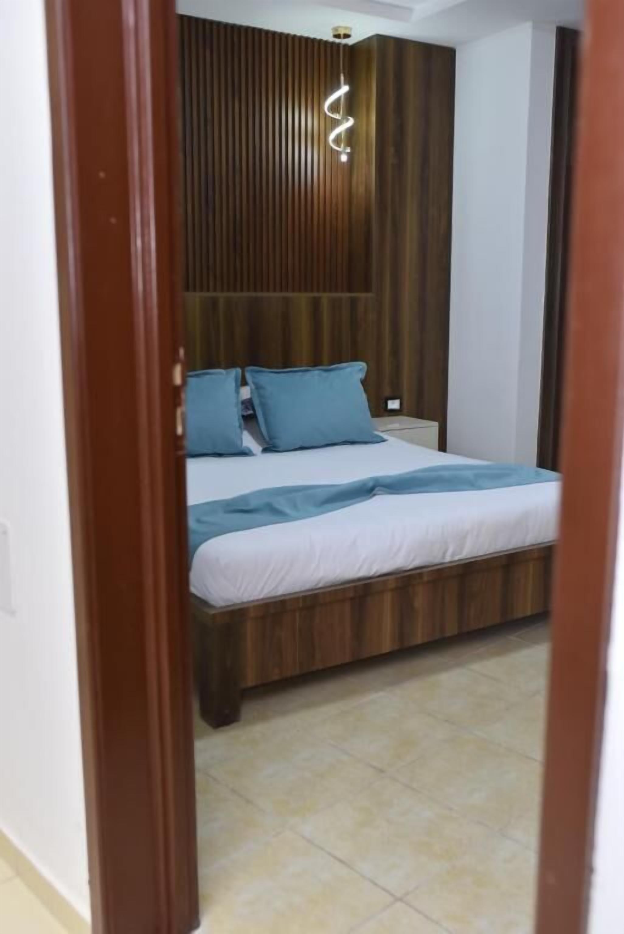 Una camera da letto con un letto, una testiera in legno e una lampada a sospensione.