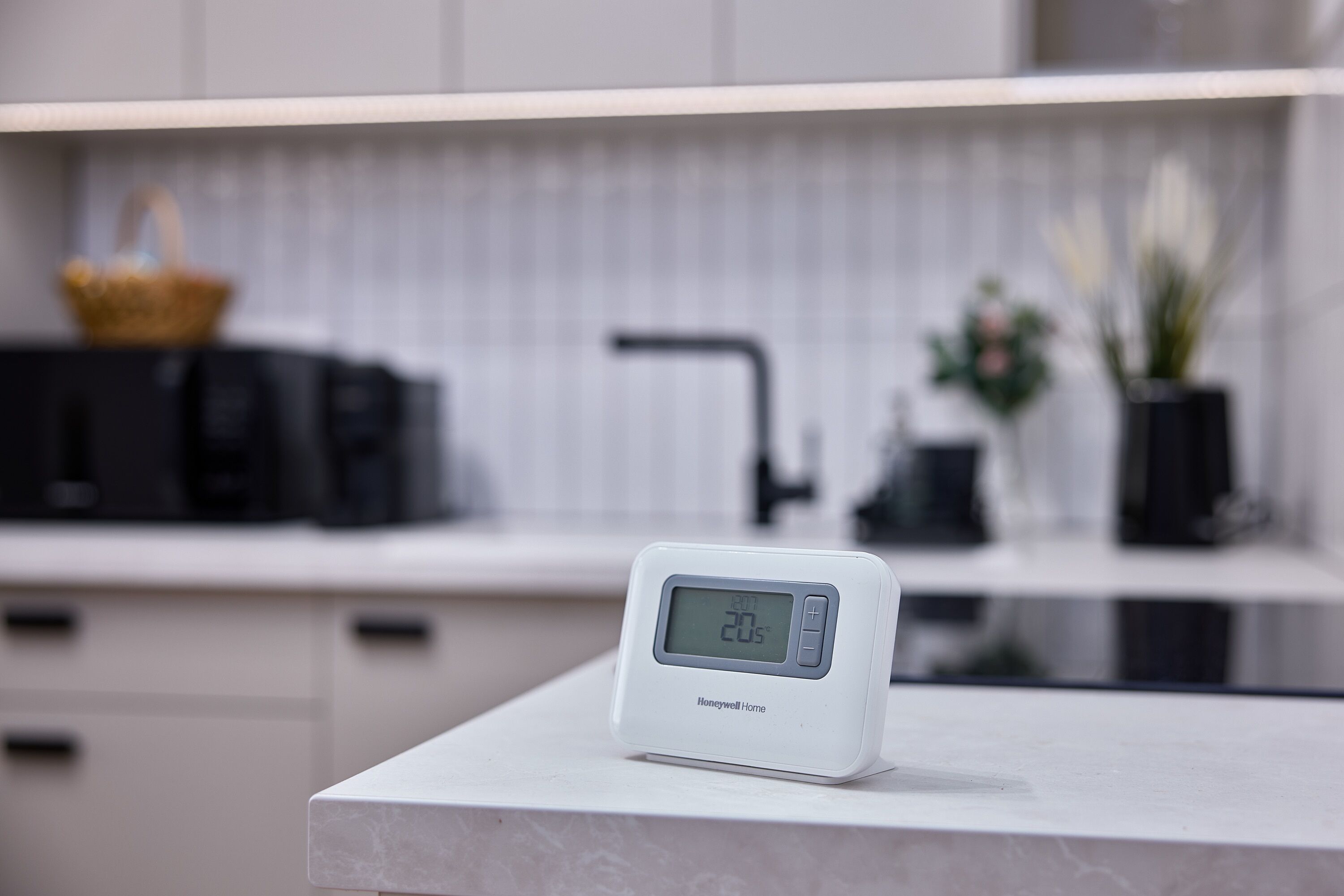 Une cuisine équipée d’une horloge numérique affichant l’heure, d’un four à micro-ondes, d’un évier et d’un panier posé sur le plan de travail.