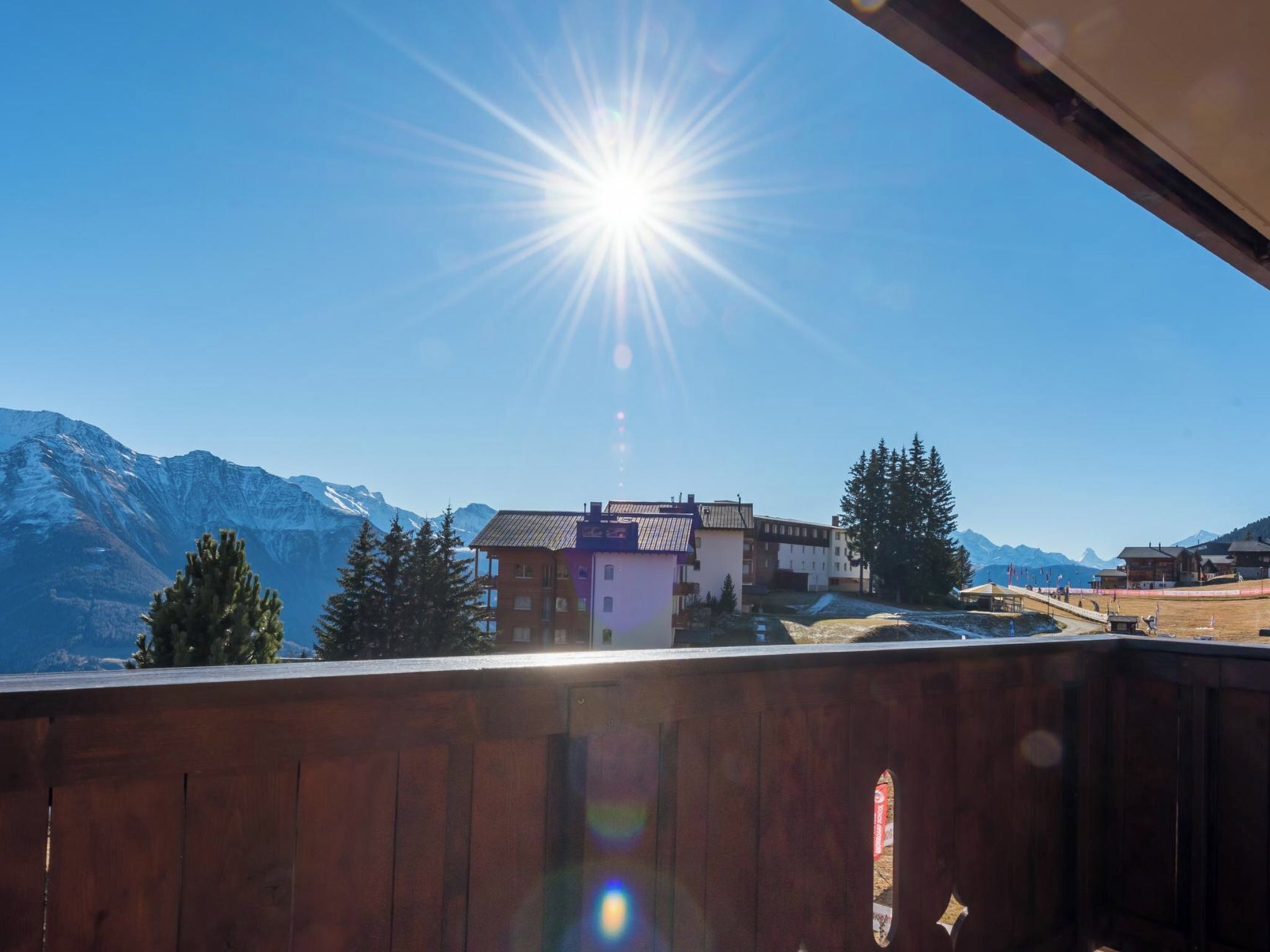 A balcony with a view of a mountain range and a building with a sloped roof.