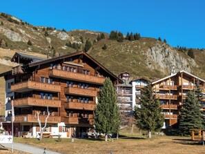 Ein mehrstöckiges Holzgebäude mit Balkonen vor einer Bergkulisse.