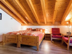 A wooden-framed room with a bed, a chair, and a nightstand. - Südlenz 41 4. OG Süd Studio, Dusche, WC 1 Zimmerwohnung, 2-Betten (Südlenz 41) by Interhome (Riederalp)