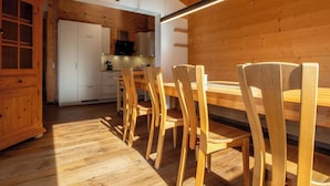 A wooden interior with a dining area, kitchen, and a cross on the wall.