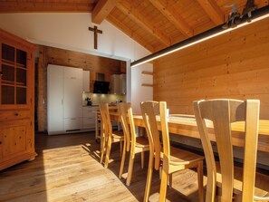 A wooden interior with a dining area, kitchen, and a cross on the wall.